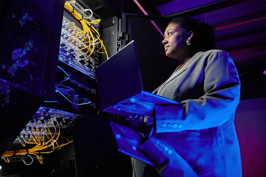 A network administrator fixing the cables on a server rack.